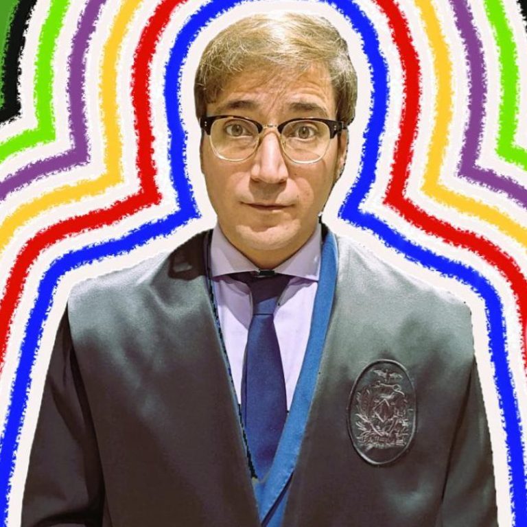 Gabriel Rodríguez Saiz Hombre con gafas y traje oscuro, rodeado de un fondo multicolor en forma de arcos.